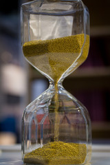 A large hourglass with bright beautiful sand on a wooden table