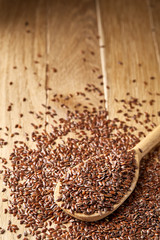Wooden spoon with flax seeds on rustic background, top view, close-up, shallow depth of field, selective focus