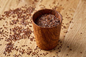 An overturned wooden bowl with linseeds on a rustic background, close-up, shallow depth of field, selective focus