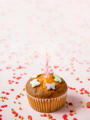 Birthday cupcakes with candles on the table. Pink background. Copy space