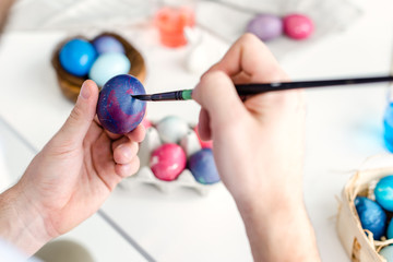 Man coloring Easter eggs with painting brush