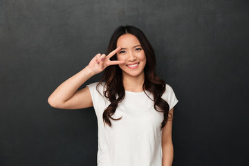 Smiling asian woman in t-shirt showing peace gesture