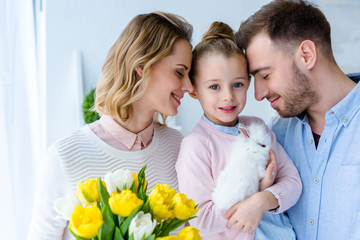 Happy family with cute bunny and spring flowers