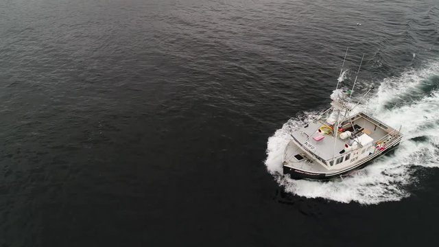 Aerial of ocean commercial fishing boat fishing with lobster traps