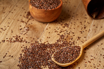 Wooden spoon with flax seeds on rustic background, top view, close-up, shallow depth of field, selective focus