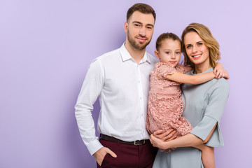 Fototapeta premium Smiling daughter and parents isolated on violet