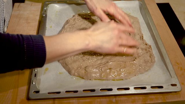 Chef spreads bread on a pan greased with oil