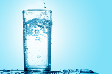 Pour drinking water into the glass with copy space