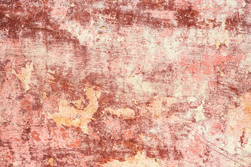 Pink-red Textured background of multi-layer flaking paint on the wall. Mixing different colors of paints in the cleaved layers on the surface. Grunge texture with a deep pattern