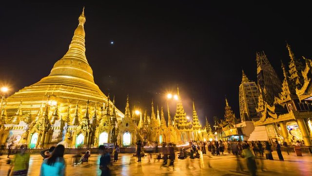 Shwedagon Pagoda in Yangon, Myanmar (Burma), time lapse view of the famous Buddhist landmark at nighttime. Zoom out.