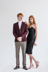 Young couple of fashion models dressed in formal wear isolated on grey