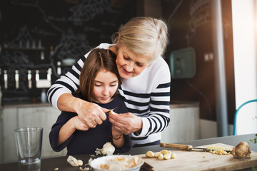 A small girl with grandmother cooking at home.