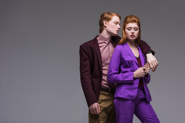 Male fashion model in jacket hugging girlfriend isolated on grey