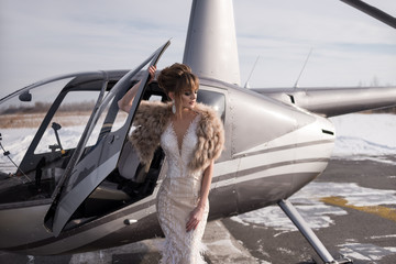 Beautiful girl in a helicopter. Bride. Wedding dress, wedding make-up and hairstyle. Fur coat....