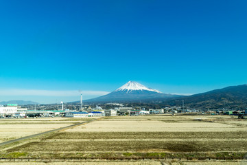 新幹線から見た冬の富士山と田んぼと青い空