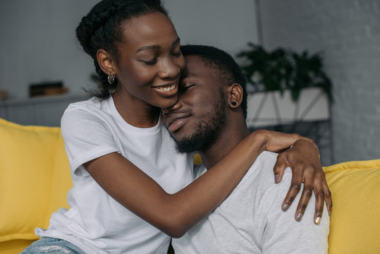 beautiful happy young african american couple in white t-shirts hugging at home