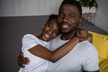 beautiful young african american couple embracing and smiling at camera