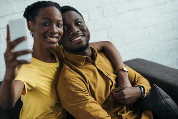 Obraz premium happy young african american couple taking selfie with smartphone