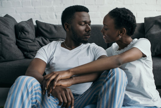 happy young african american couple in pajamas smiling each other at home