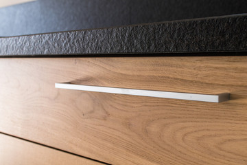 New industrial kitchen detail of a drawer. Kitchen in new apartment in natural oak with granite and steel.