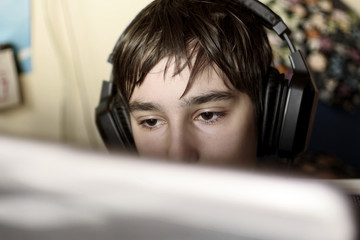 Close up of young boy staring at laptop screen during playing computer games, chatting on the...