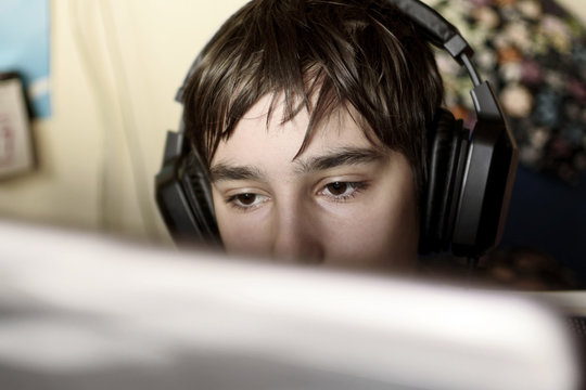 Close up of young boy staring at laptop screen during playing computer games, chatting on the Internet or viewing video
