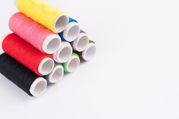 Heap of bobbins of new colorful threads on white background