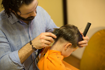 Fototapeta premium Child getting haircut at the hairdresser salon