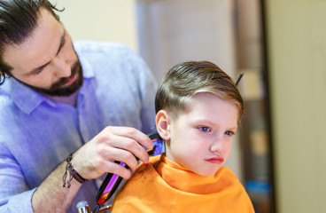 Child getting haircut at the hairdresser salon