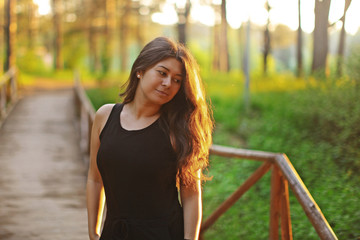young woman in the park in the forest at sunset