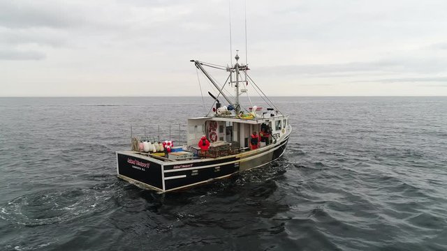 Aerial shot of commercial ocean fishing boat checking lobster traps