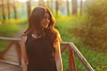young woman in the park in the forest at sunset