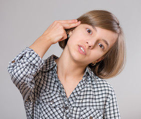 Fototapeta premium Close-up emotional portrait of caucasian girl. Sad schoolgirl making an imaginary gun shoot and looking at camera. Funny cute child on gray background.
