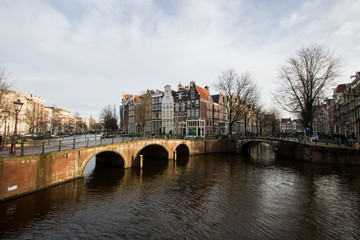 Bridges and canal crossing in Amsterdam with houses overlooking the canal. Street system of the Dutch capital with bridges and canals. Typical view in Amsterdam