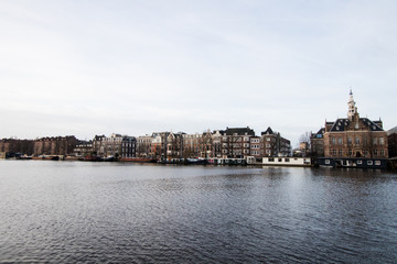 Obraz premium Multicolored houses in Amsterdam on the main canal of the city. Typical Amsterdam Dutch houses with many windows and vertically developed. Boats at bottom