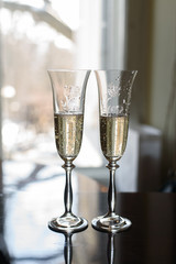 two wedding decorated transparent glasses with champagne on the wooden table