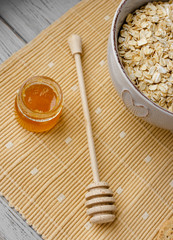 Healthy breakfast: oatmeal cereal, cup of milk, jar of homemade jam, oatmeal cookies. Flowers in a vase on a background. Coconut biscuits on a saucer. Exquisite romantic breakfast. Food blog ideas