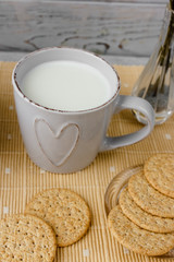 Healthy breakfast: oatmeal cereal, cup of milk, jar of homemade jam, oatmeal cookies. Flowers in a vase on a background. Coconut biscuits on a saucer. Exquisite romantic breakfast. Food blog ideas