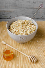 Healthy breakfast: oatmeal cereal, cup of milk, jar of homemade jam, oatmeal cookies. Flowers in a vase on a background. Coconut biscuits on a saucer. Exquisite romantic breakfast. Food blog ideas