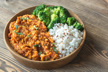 Bowl of red lentil curry with white rice and broccoli