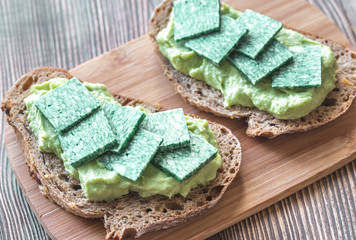 Slices of toasted bread with avocado paste and basil cheese