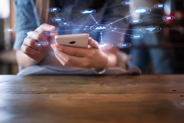 Hand of woman using smartphone on wooden table,Space for text or design.