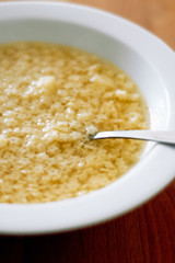 Typical German homemade chicken broth with tiny, Italian star-shaped noodles, called Stelline, in white soup plate with spoon as prevention or remedy when having a cold