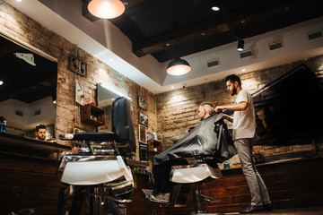 Fototapeta na wymiar Making hair look magical. Young bearded man hairdresser at barbershop. Soft focus, noise