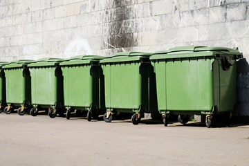 A row of green garbage containers on the city street. - 194989410