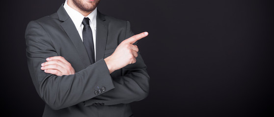 Business man pointing finger at copy space on black background
