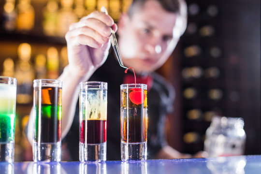 Bartender lays cherry in a shot at the bar