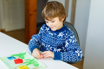 Little kid boy making paper origami tulip flowers for a postcard for mother's day or birthday. Cute child of elementary class school doing handicraft