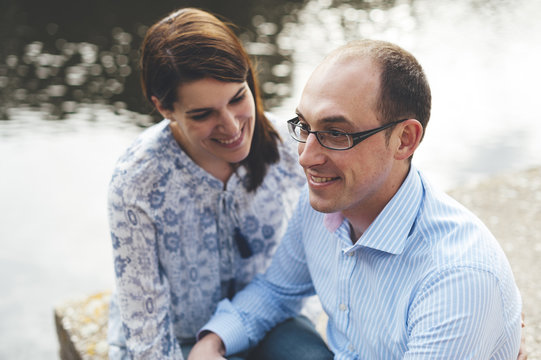 Couple sharing a good time seated in a pier close to a lake
