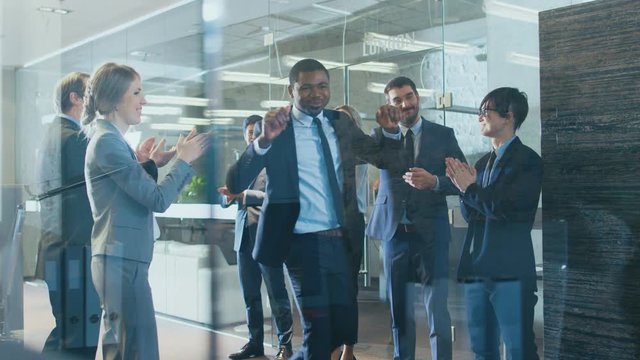 Black Businessman Got Big Promotion, Walking Path of Success, His Colleagues Cheer and Applaud. Stylish Diverse Office Filled with Happy People. Shot on RED EPIC-W 8K Helium Cinema Camera.